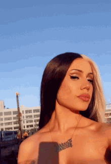 a woman wearing a necklace that says ' bitch ' on it takes a selfie