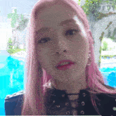 a woman with pink hair is wearing a black top and earrings