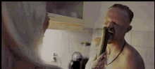 a shirtless man is eating a cucumber in a kitchen while a woman watches .