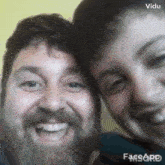 a man with a beard and a woman with a beard are smiling for a picture .