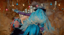 a woman in a blue dress is dancing with another woman in a purple dress in a cave .