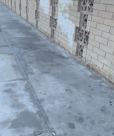a brick wall along a sidewalk with a few cars parked behind it