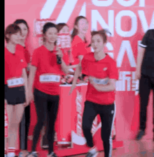 a group of women in red shirts are standing in front of a sign that says nov