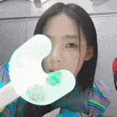 a woman holding a green object in front of her eye