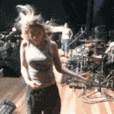 a woman is dancing on a stage with drums in the background