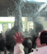 a crowd of people are gathered in a room with smoke coming out of the ceiling .