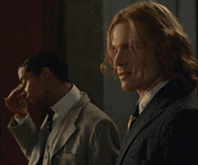 a man in a suit and tie is standing next to another man