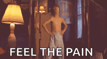 a shirtless boy is standing in front of a lamp with his hands on his hips .