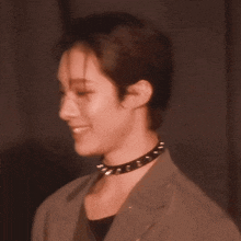 a woman wearing a choker and glasses looks to the side