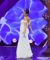 a woman in a white off the shoulder dress is dancing on a stage
