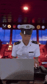 a man in a navy uniform is typing on a laptop