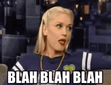 a woman in a blue shirt is sitting in a stadium with the words blah blah blah written on her face .