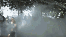 a woman is taking a picture of a group of people in a foggy park