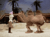 a woman standing next to a camel with a cat 's head on it