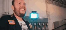 a man with a beard is smiling in a room with a light behind him .