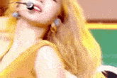 a close up of a woman wearing a yellow top and earrings .