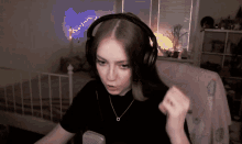 a woman wearing headphones and a necklace with a small o on it