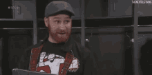 a man with a beard is wearing a hat and a plaid jacket .