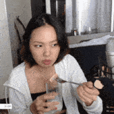 a woman is holding a glass of water and a piece of food on a fork with a price tag of $ 1,000 on the bottom