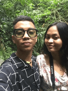 a man wearing glasses and a woman wearing a canon camera strap