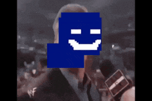 a man in a suit is holding a microphone and has a blue square with a white smile on it