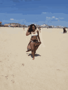 a woman in a bikini is walking barefoot on a sandy beach