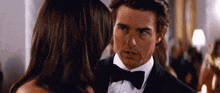 a man in a tuxedo talks to a woman in a dress