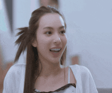 a woman with her hair in a ponytail looks at the camera and smiles