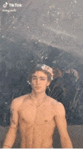 a shirtless man is standing in the rain with a necklace on his neck .