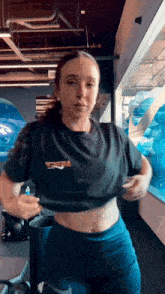 a woman is standing in a gym wearing a crop top and shorts .