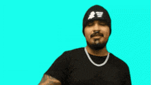 a man wearing a beanie and a necklace with the letter w on the bottom right