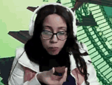 a woman wearing headphones and glasses is holding a piece of food in her hand .
