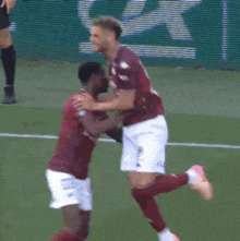 a group of soccer players are hugging each other on a soccer field .