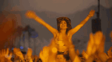 a woman is dancing in front of a crowd at a music festival with the word campbells on the bottom right