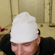 a man wearing a black shirt and a white hat smiles