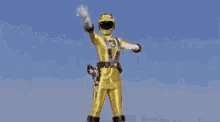 a yellow power ranger is standing in the rain with his arms in the air .