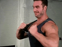 a man with a beard is wearing a blue tank top and smiling .