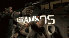 a man pointing a gun at another man with the word gramkos written on the wall behind him