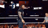 roman reigns is walking out of the ring during a wrestling match in front of a crowd .