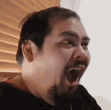 a man with a beard is making a face with his mouth wide open .