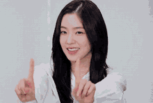 a woman with long dark hair is wearing a white shirt and necklace .