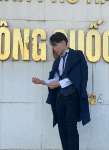 a man in a suit and tie stands in front of a sign that says ong