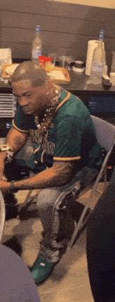 a man in a green shirt is sitting in a chair in front of a table .