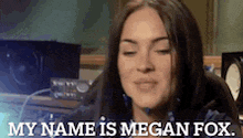 a woman is sitting at a desk with her eyes closed and says my name is megan fox