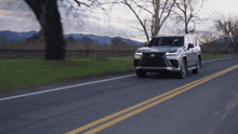 a silver lexus is driving down a road with mountains in the background