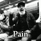 a man wearing a face mask is sitting on a train with the word pain written on it