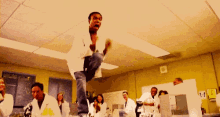 a man in a lab coat is jumping in the air in front of a group of people