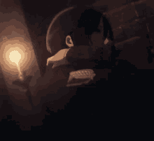 a close up of a person 's face in a dark room with a candle in the background .