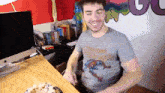 a man wearing a spiderman shirt is sitting at a table