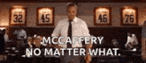 a man in a suit and tie is standing in front of a wall with jerseys on it and says `` no matter what . ''